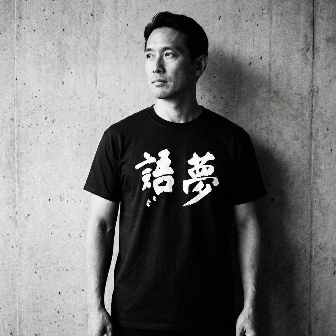 Person wearing a black t-shirt with white text against a concrete wall