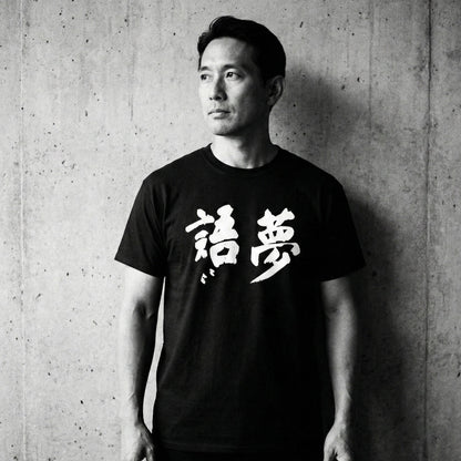 Person wearing a black t-shirt with white text against a concrete wall