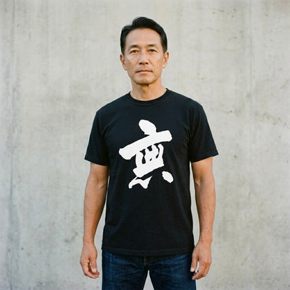 Man wearing a black t-shirt with a white symbol against a gray concrete wall