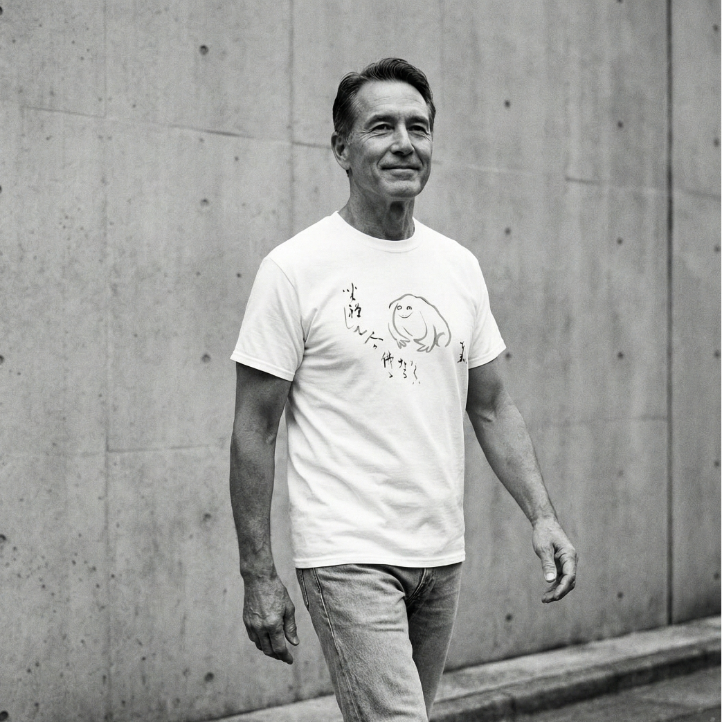 Man wearing a white t-shirt with a graphic design against a concrete wall.