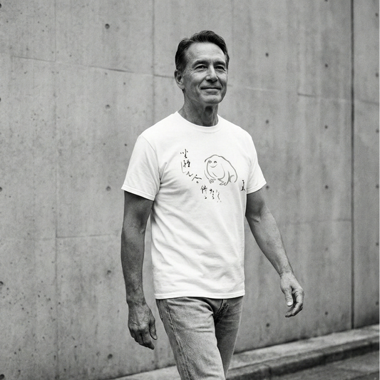 Man wearing a white t-shirt with a graphic design against a concrete wall.