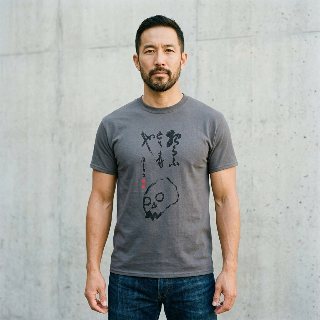 Man wearing a gray t-shirt with a graphic design against a concrete wall.